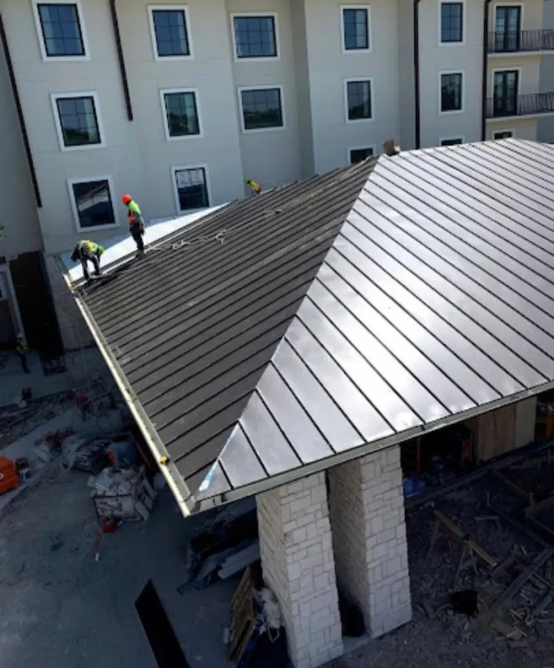 Crew installing standing seam metal roof panels on a commercial project in New Sewickley